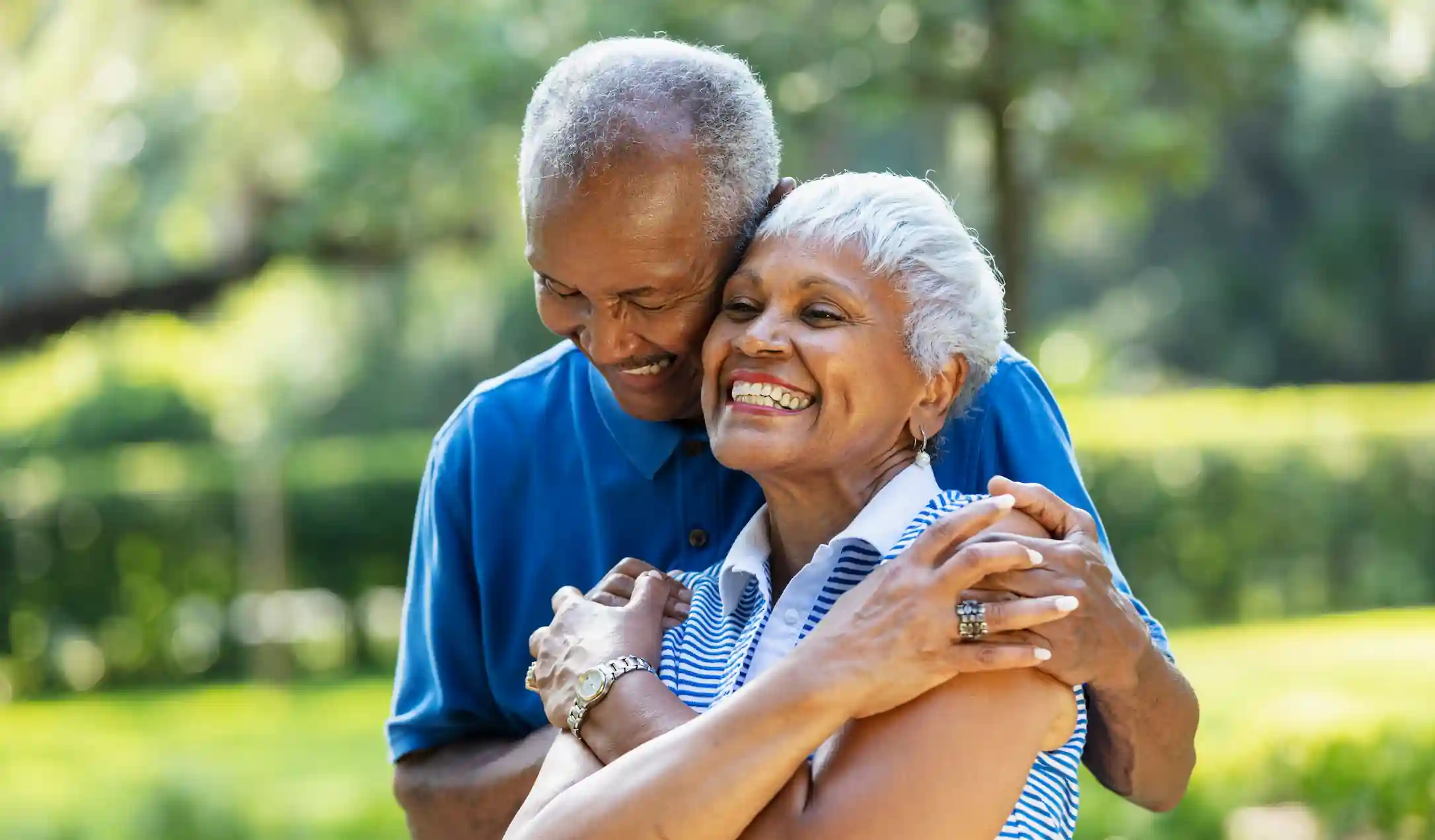 A smiling senior couple hugging outdoors